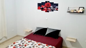 A bedroom with a bed, a wall-mounted shelf with decorative items, and a single light fixture. - 2.simple, Sobre, Proche Mosquée et Belle Plage (Marsa Ben M'Hidi)