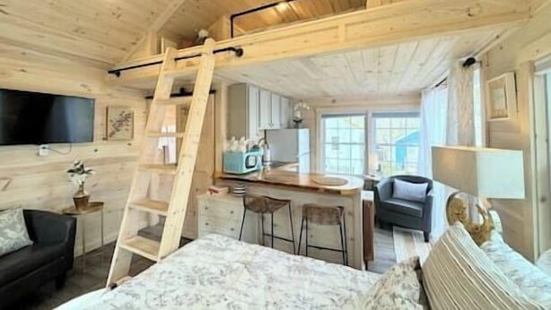 L’intérieur d’une cabane en bois comprend une chambre à coucher située en mezzanine, un coin cuisine et un espace repas.