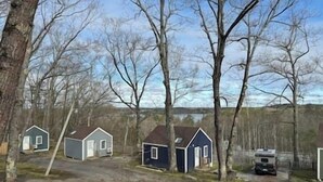 Une rangée de petites maisons à un seul étage, dotées de garages attenants, entourées d’arbres et baignées par un ciel dégagé.