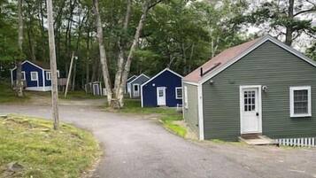 Une rangée de cabanes, avec un chemin de gravier menant à elles, le tout entouré d’arbres.