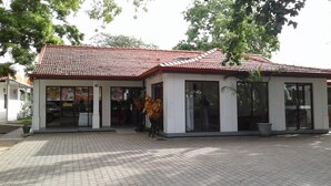 A building with a tiled roof, large windows, and a paved entrance area. - Trinco Rest House (Trincomalee)