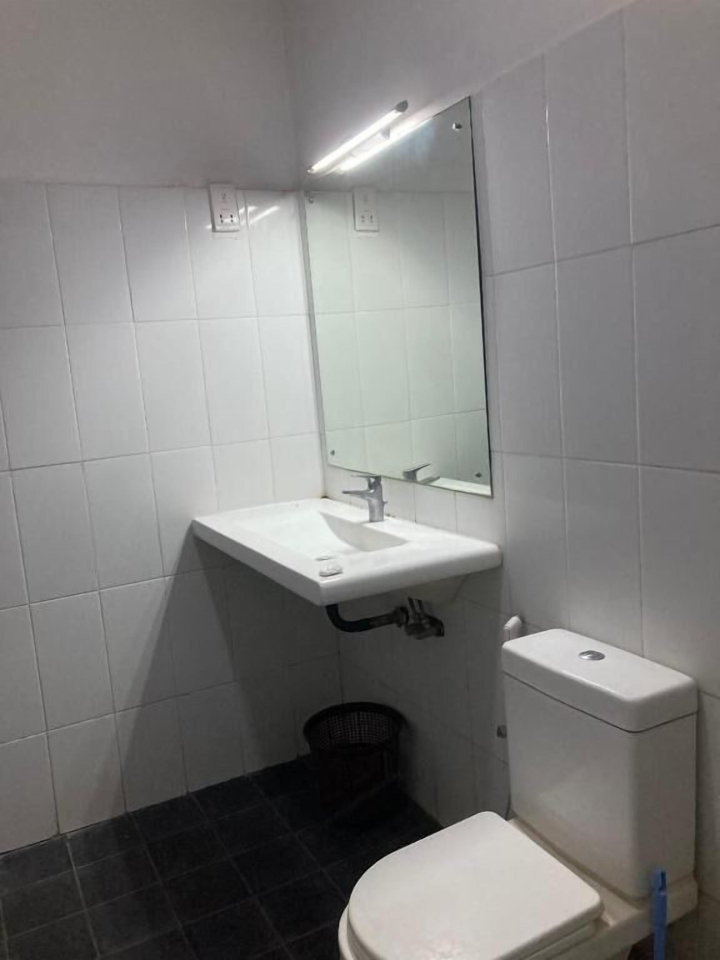 A small, clean bathroom with white tiles, a white sink, a mirror, and a toilet.