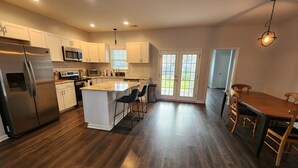 A modern kitchen with a central island, stainless steel appliances, and a dining area with wooden chairs.