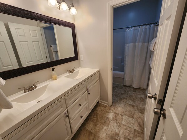 A bathroom with a double sink, a large mirror, and a shower curtain.