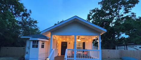 A small, single-story house with a porch, a small attached garage, and a well-maintained lawn.