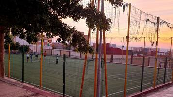 Una cancha deportiva con una red, rodeada por una valla y árboles.