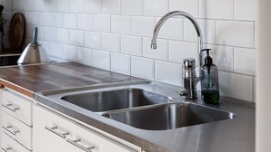 A kitchen with two stainless steel sinks, a wooden countertop, and a white tiled backsplash. - Semesterboende på Öland (Kalmar län)