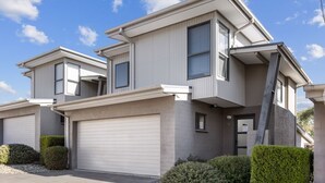 A two-story residential building with a garage, a covered entryway, and a small porch. - NorthStar 2, perfectly situated in the heart of Jindabyne (Jindabyne)