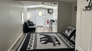 A bedroom with a bed, a rug, a desk, and a chair.