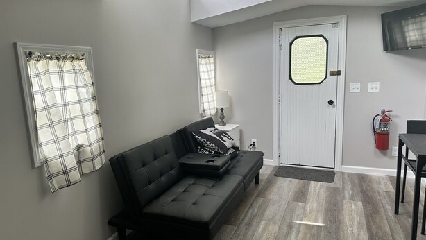 A living room with a dark sofa, a small table, and a door with a window.