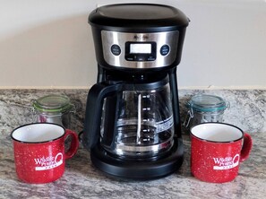Eine Kaffeemaschine mit zwei roten Tassen, beschriftet mit 'Wildlife Prairie Park', auf einer Küchenarbeitsplatte.