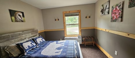 A bedroom with a bed, a window, and wall-mounted artwork.