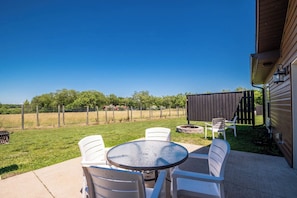 A patio with a round table and chairs, a fire pit, and a fenced yard.