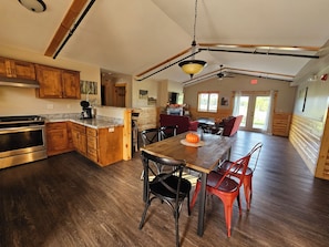 A spacious kitchen with wooden cabinets, a central island, and a dining area with red chairs.