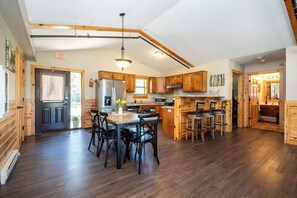 A spacious kitchen with wooden cabinets, a central island, and a dining area with chairs.