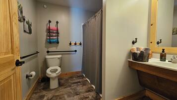 A bathroom with a toilet, a shower curtain, a sink with a mirror, and a towel rack.