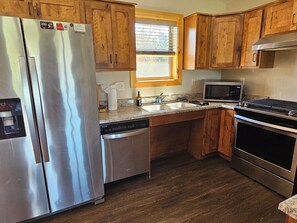 A kitchen with wooden cabinets, stainless steel appliances, a window, and a microwave.