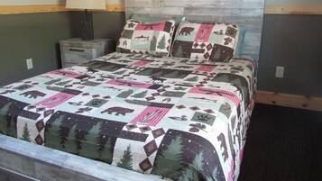Una cama con colcha de estampados de fauna, una lámpara de noche y un cabecero de madera.
