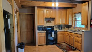Una cocina con gabinetes de madera, una estufa negra y una cafetera.