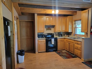 A kitchen with wooden cabinets, a black stove, and a coffee maker.