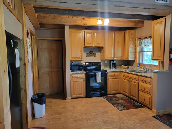 A kitchen with wooden cabinets, a black stove, and a coffee maker.