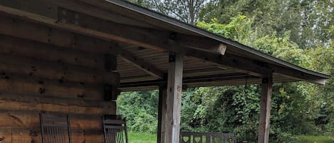 Une cabane en bois dotée d’un porche couvert, de meubles d’extérieur et d’un foyer.