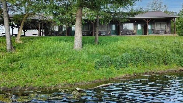 Un chalet doté d’un porche abrité, d’une pelouse et d’un plan d’eau.
