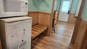 A laundry area with a microwave, dryer, and wooden bench.