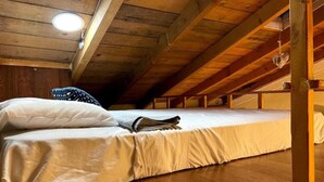 A single bed in a loft-style room with wooden beams and a sloped ceiling.
