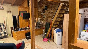 A rustic room with exposed brick walls, wooden beams, and a loft area.
