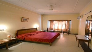 Een hotelkamer met een groot bed, een bureau, een stoel, een televisie en een raam met gordijnen.