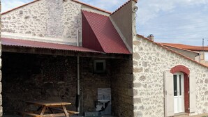 Un edificio de piedra con techo rojo, un banco de madera y una puerta.