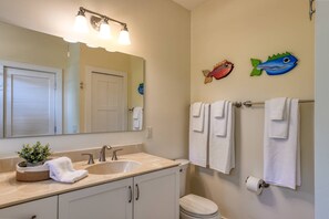 Un baño con lavamanos, espejo, toallero, inodoro y decoración de peces en la pared.