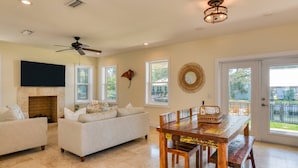 A spacious living room with a fireplace, a ceiling fan, and a dining area with a wooden table and benches. - Castaway Cottage (St. Augustine)