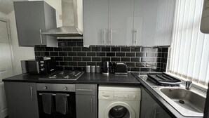 A compact kitchen with a dishwasher, oven, and a washing machine. - City Escape - Charming 2-bed House (Leeds)