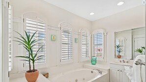 A modern bathroom with a freestanding bathtub, white cabinetry, and a large mirror. - Endless Sea (Santa Rosa Beach)