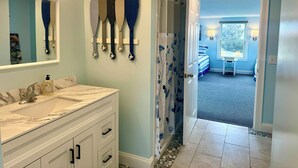 A bathroom with a marble sink, a mirror, and a shower with a floral shower curtain. - Top Mast Resort-Anchor House, Private Beach Access. (North Truro)