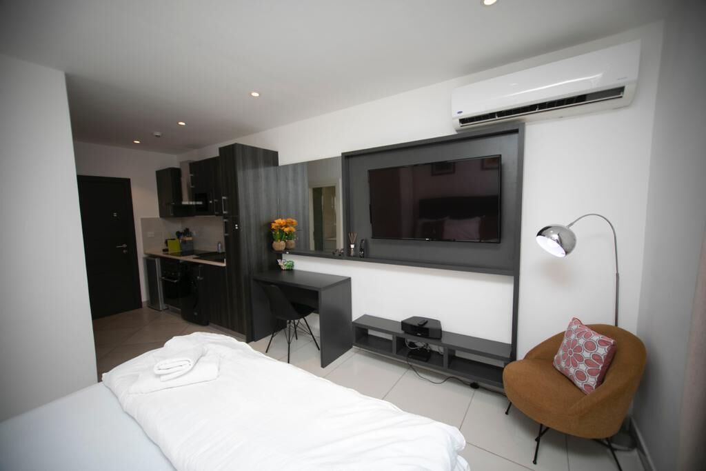 Een moderne hotelkamer met een bed, een bureau, een stoel, een televisie en een bijzettafeltje.