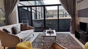 A modern living room with a sofa, a yellow armchair, a coffee table, and a TV.