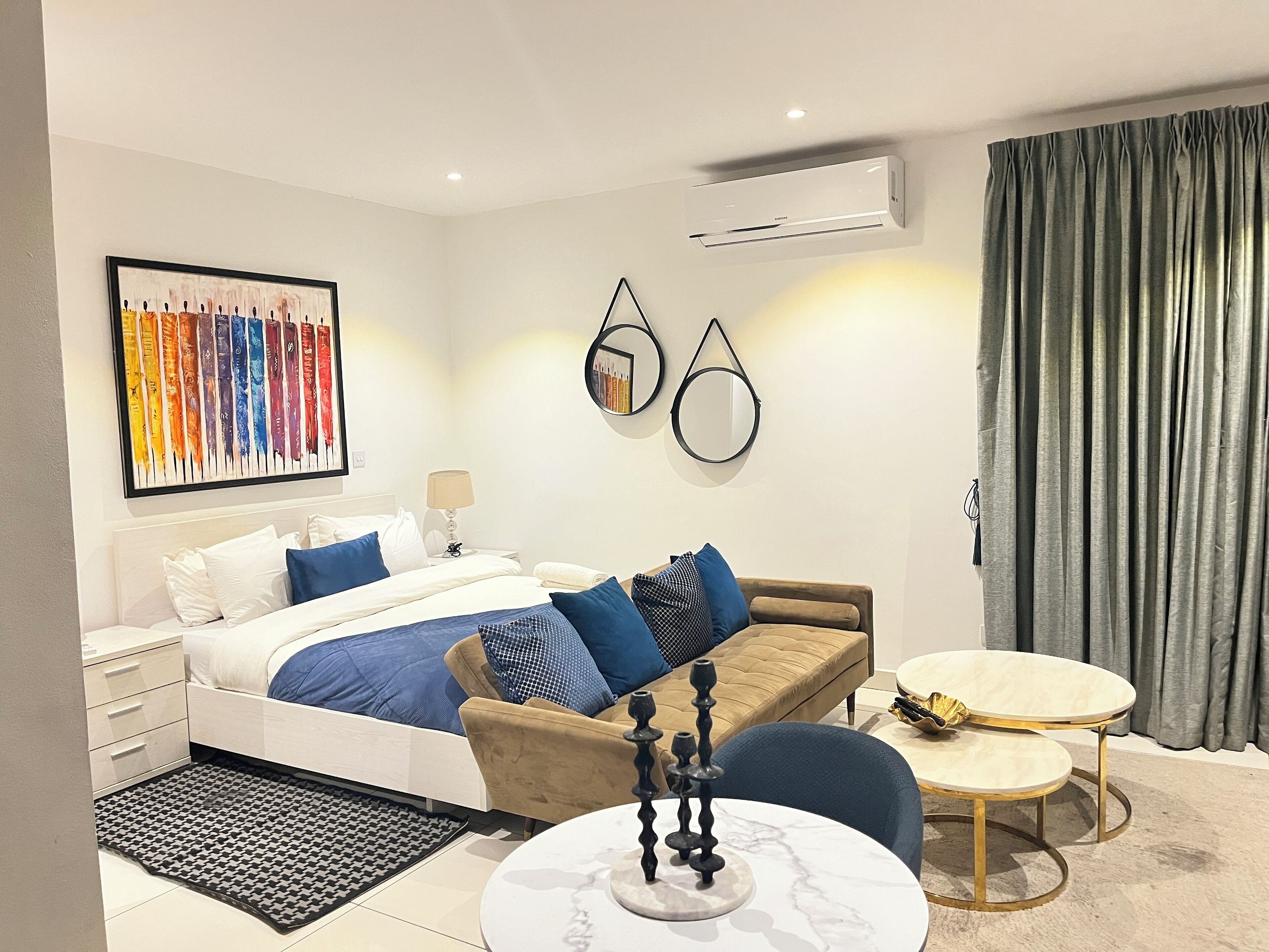 A modern hotel room with a bed, a sofa, a small table, and a decorative item.