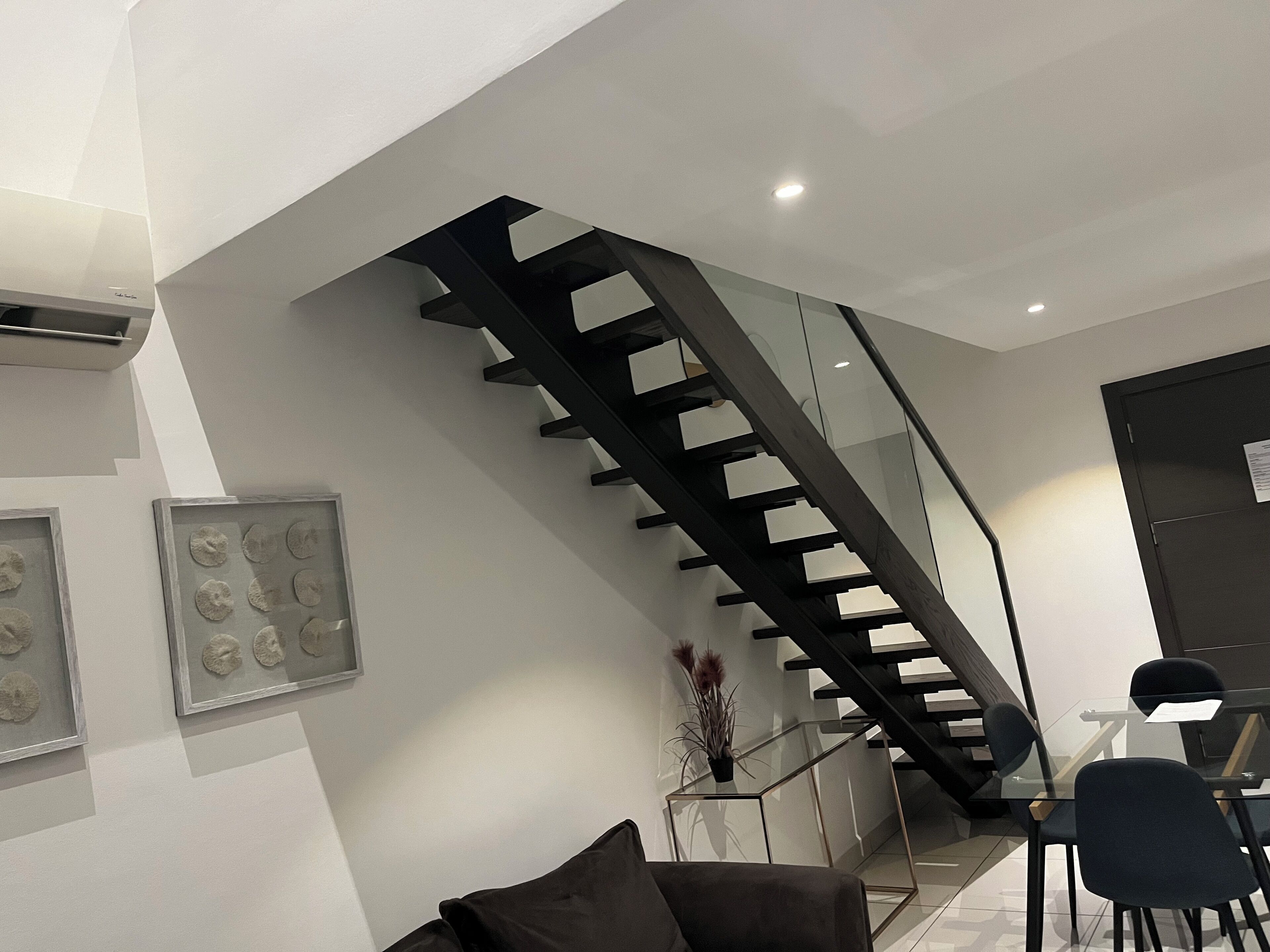A modern interior with a staircase, a dining area, and artwork on the walls.