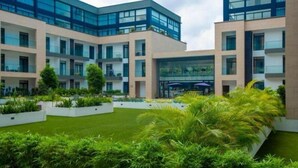 A modern building with multiple floors, large windows, and a central courtyard with greenery.