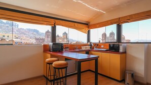 Una cocina moderna con encimera de madera, un lavamanos y vistas a un paisaje urbano a través de amplios ventanales.