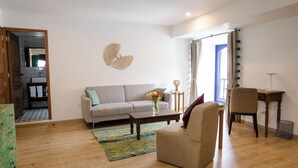 Una sala de estar con un sofá, un sillón, una mesa de centro y una mesita auxiliar con un jarrón de flores.
