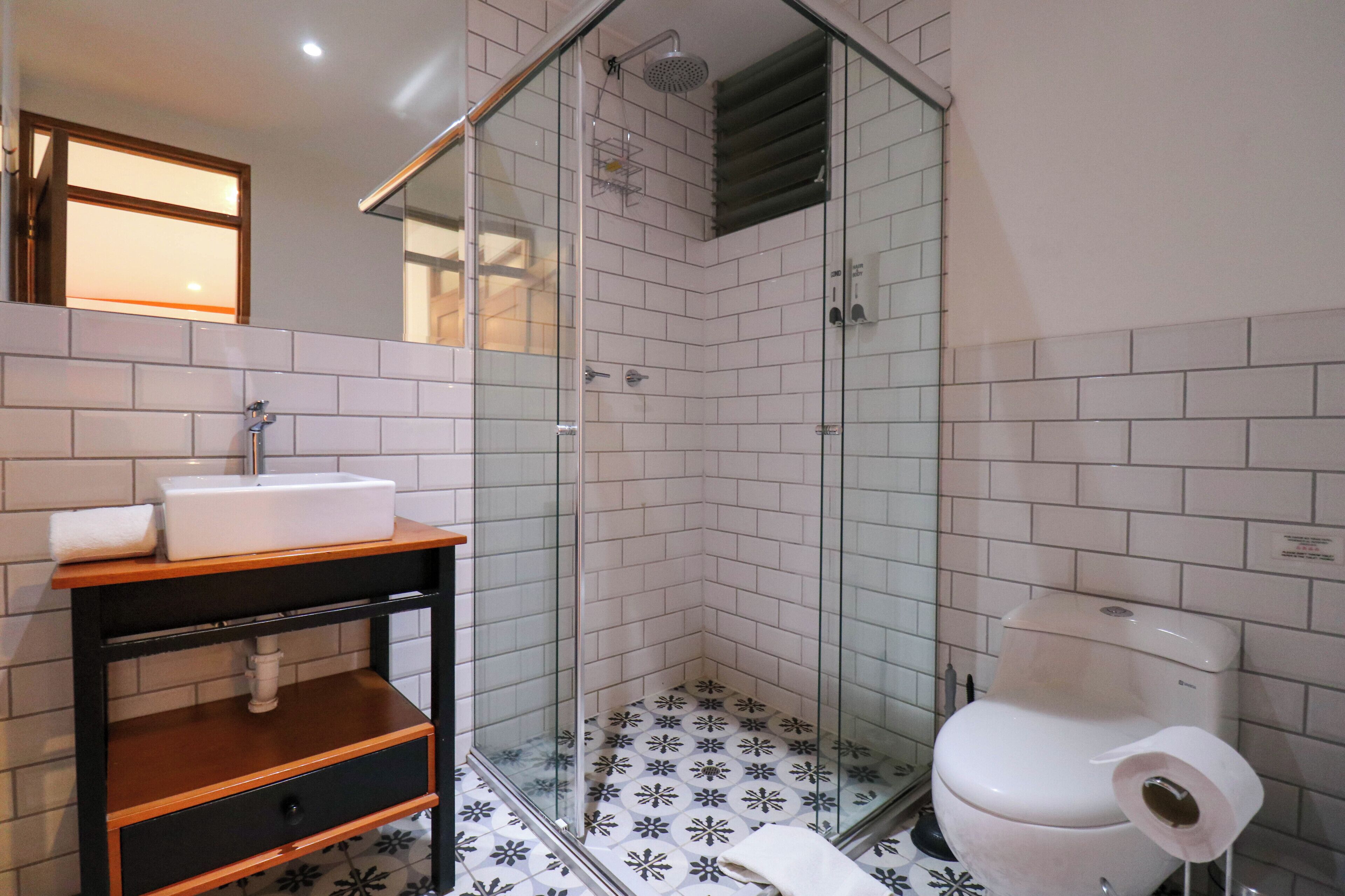A bathroom with a glass-enclosed shower, a white sink, and a toilet.
