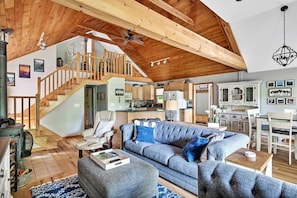 Relax in this inviting living area with a comfortable sofa, wooden staircase, and dining space.