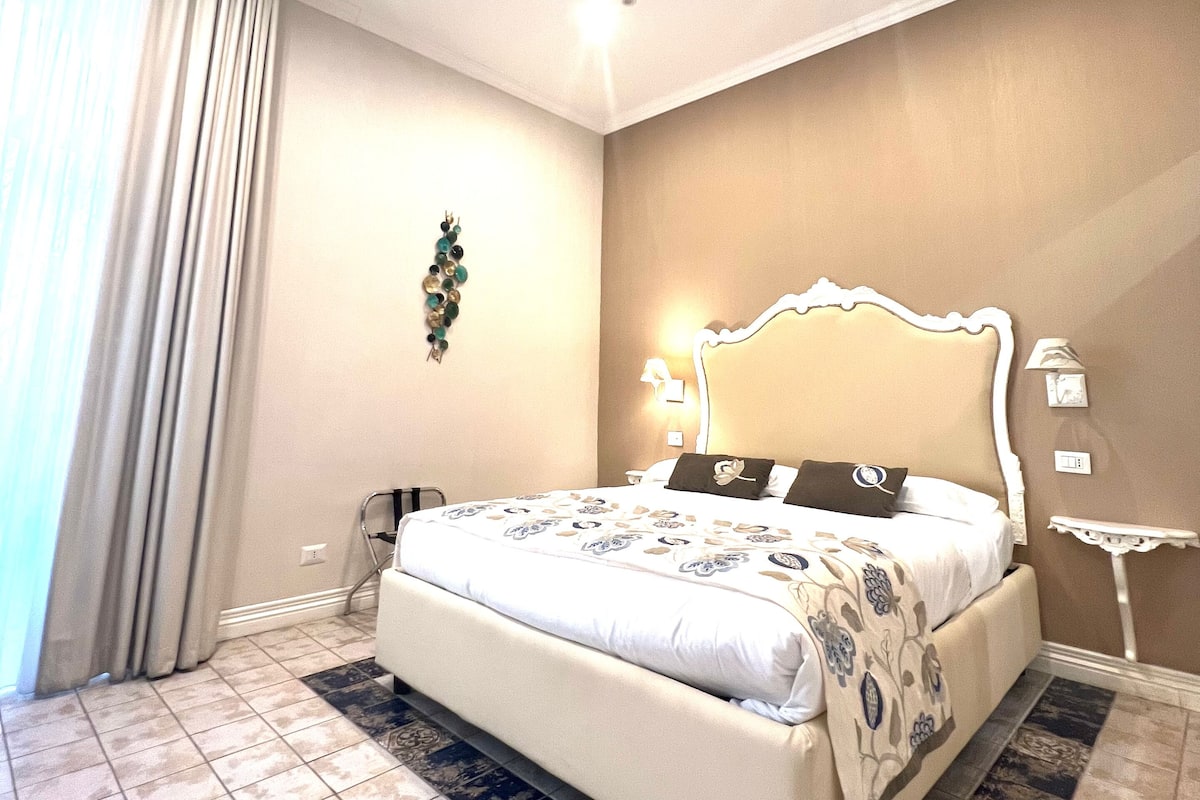 Habitación de hotel con una cama grande, una mesita de noche, una lámpara de pared y un adorno en la pared.