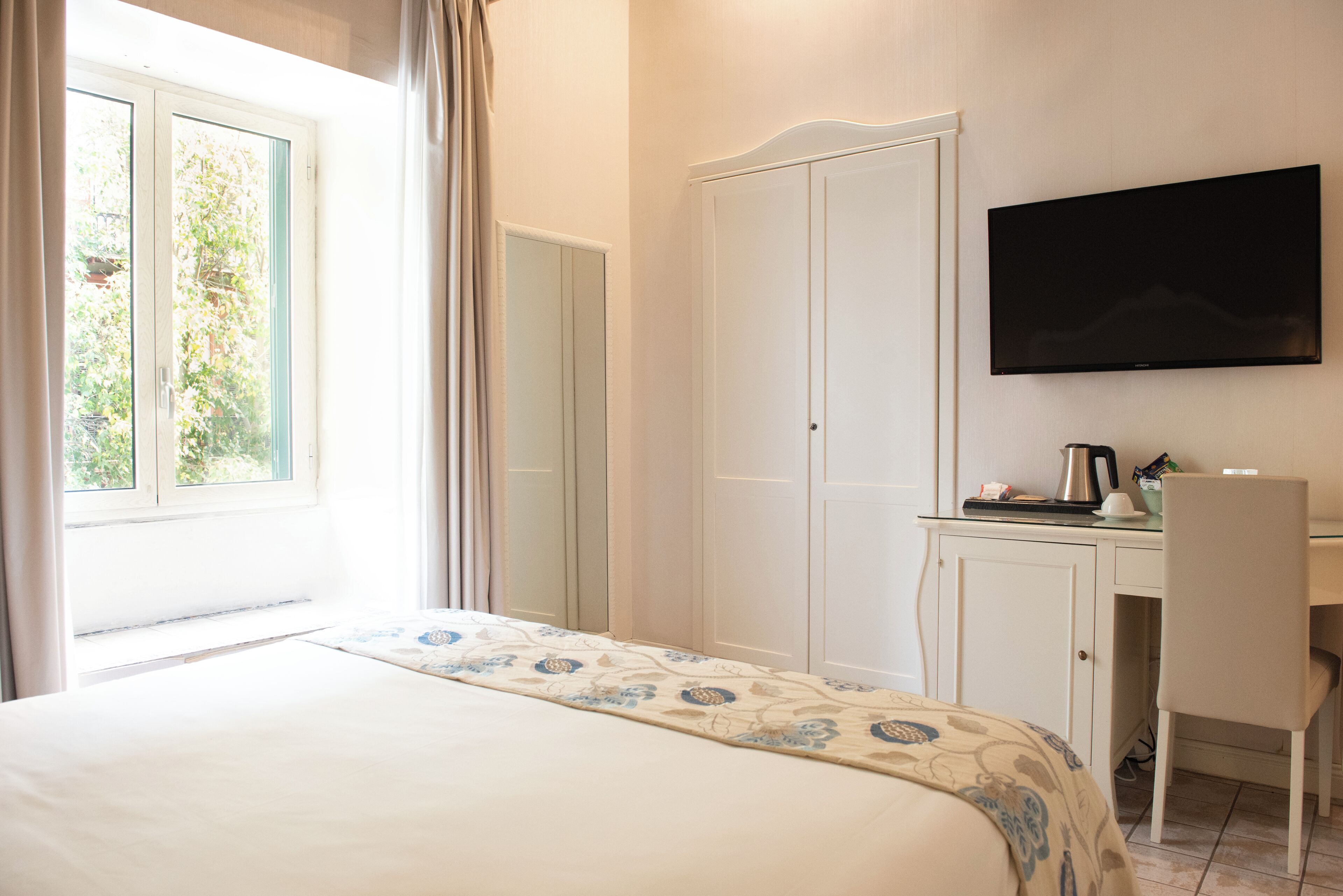 Une chambre d’hôtel comprenant un lit, un bureau, une chaise, une télévision et une armoire.