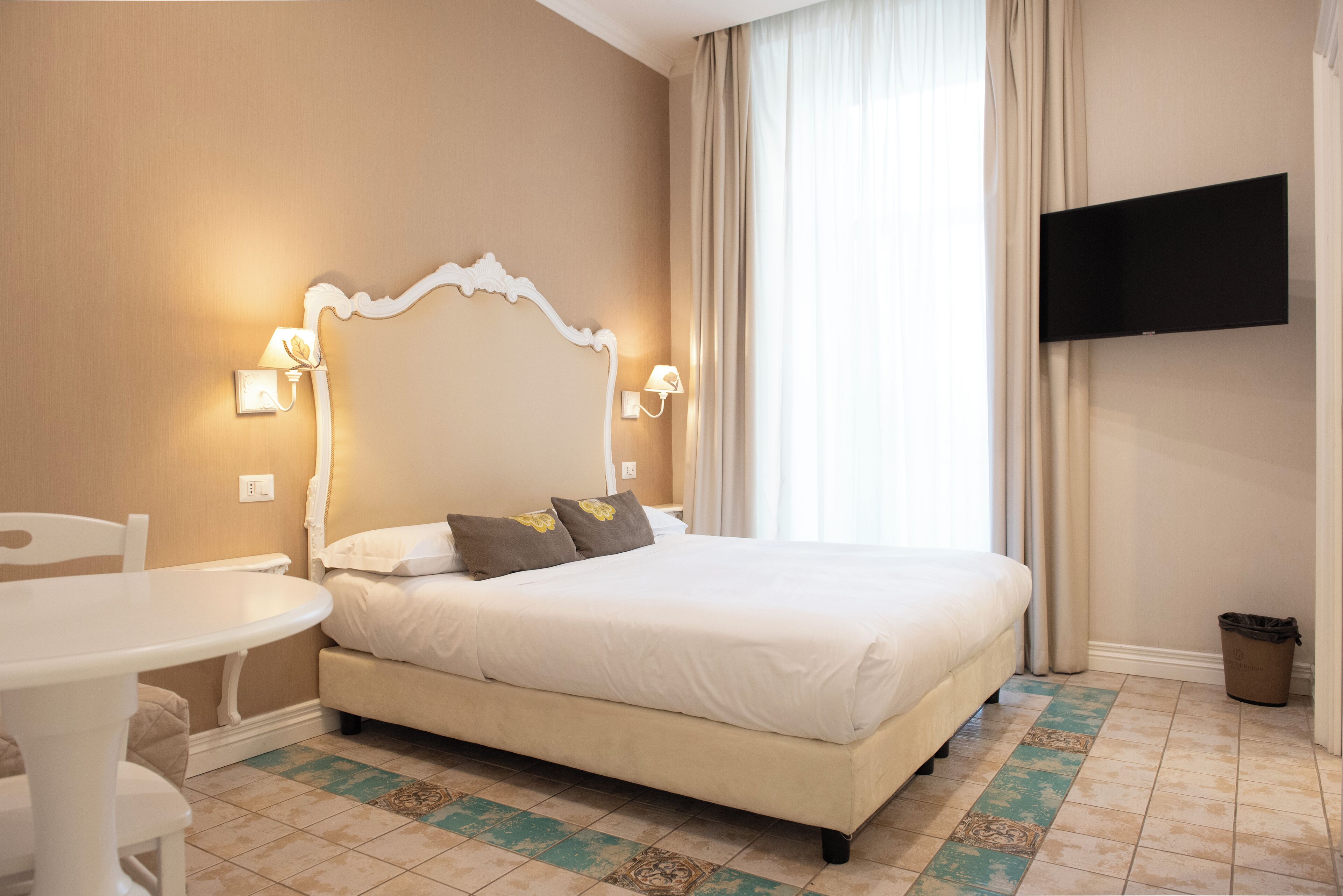 A hotel room with a bed, a TV mounted on the wall, a small table, and a chair.