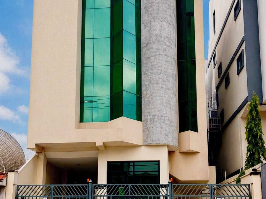 Un bâtiment moderne doté d’une façade en verre remarquable, d’une structure cylindrique et d’une entrée sécurisée par un portail.
